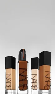 NARS foundation bottles in multiple shades displayed together, showcasing a range of complexion tones for a natural-looking makeup base