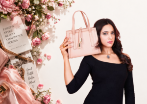 “Woman in a black outfit holding a stylish pink handbag with floral fashion decor”