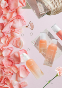 Laneige skincare products arranged with a pink facial roller, floral accessories, and rose petals in an aesthetic beauty flat lay