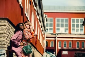 Two women wearing stylish colorful outfits and posing together for a trendy street style fashion look