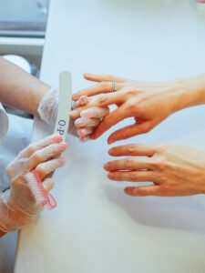 Nail technician gently shaping and cleaning a client's natural nails during a professional manicure.