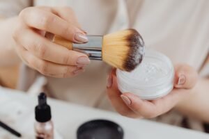 Makeup brush applying setting powder from a loose powder container for a smooth, flawless makeup finish
