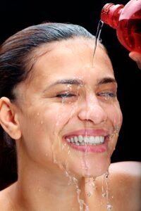 Woman rinsing her face with water for fresh, hydrated skin | AymaxBlush