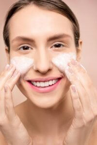 Woman gently applying a cleanser to her cheeks as part of a skincare routine