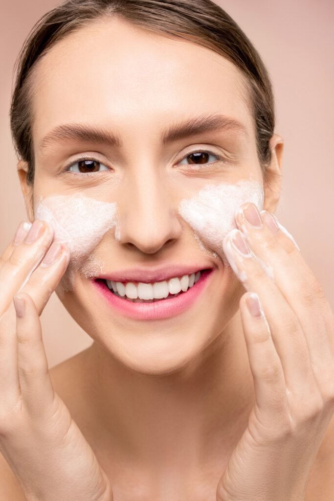 Woman gently applying a cleanser to her cheeks as part of a skincare routine