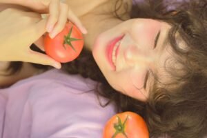 Woman holding fresh tomatoes as part of a natural skincare and healthy beauty routine