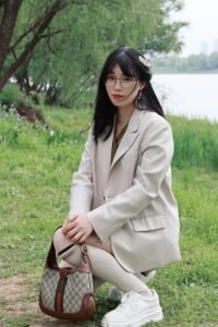 Woman wearing a cream blazer and Gucci designer handbag in a park