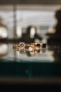 Elegant gold engagement ring and wedding band displayed on a reflective surface