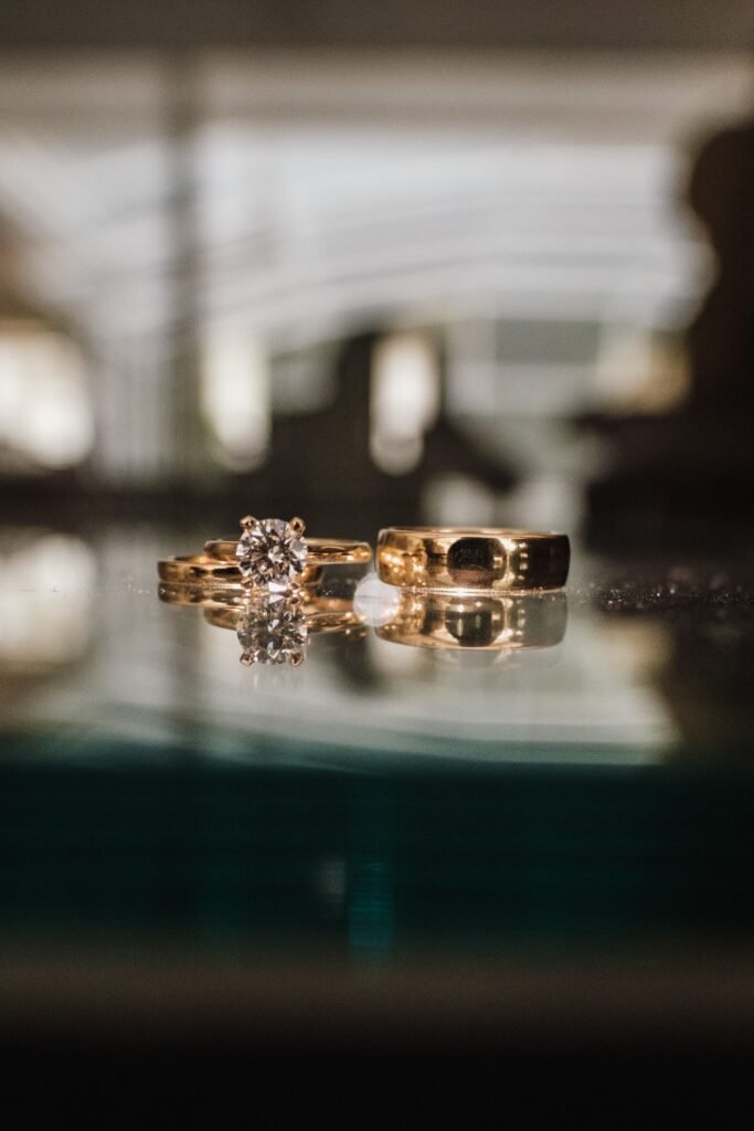 Elegant gold engagement ring and wedding band displayed on a reflective surface