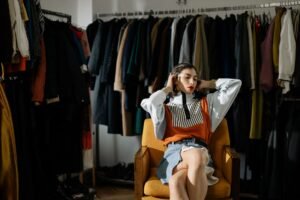 Woman choosing an outfit while surrounded by clothes in a stylish wardrobe