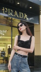 Woman wearing a black crop top and high-waisted jeans outside a Prada fashion store