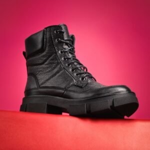 Black lace-up platform boots with a chunky sole on a bright pink background